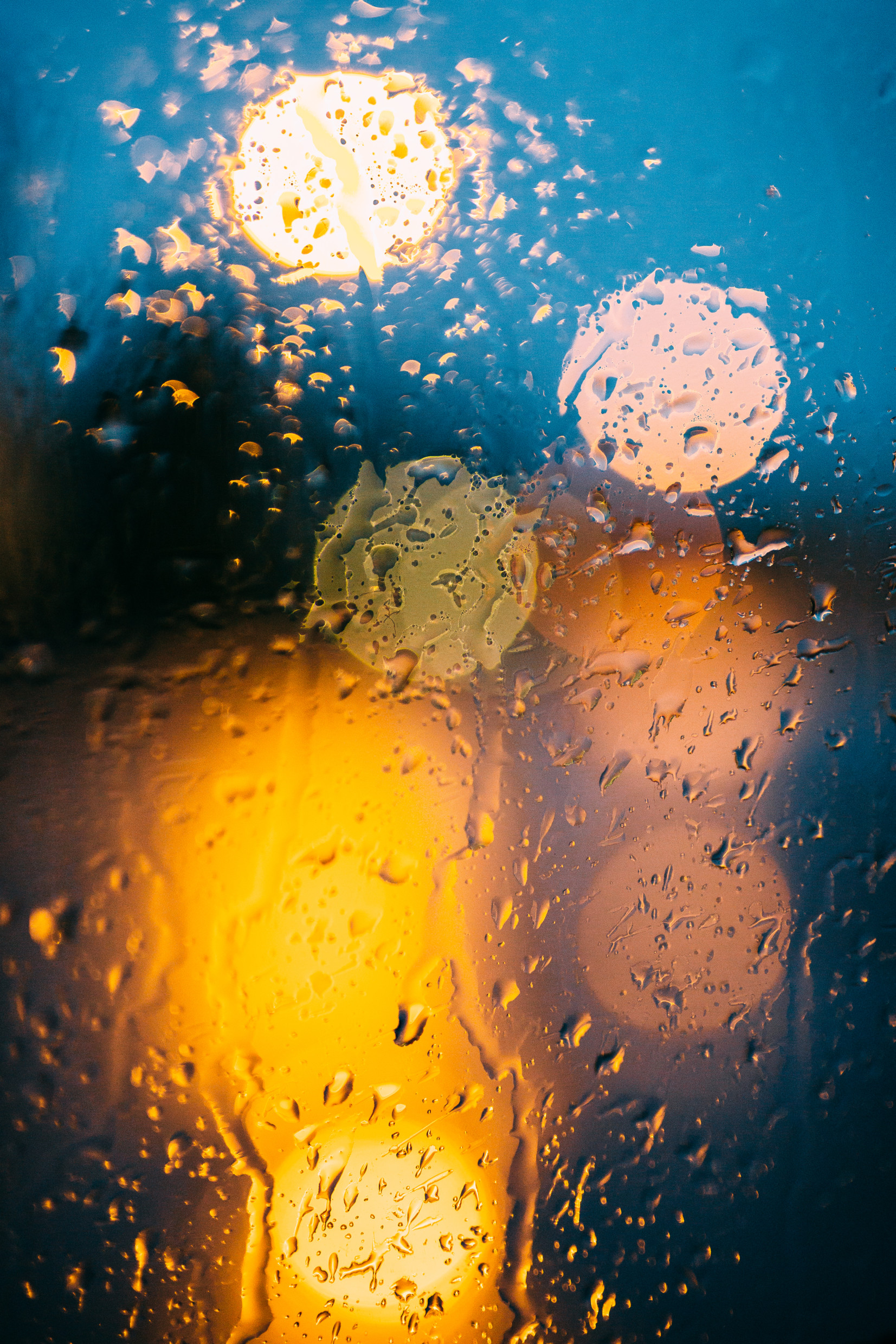 Sadepisaroita ikkunassa, taustalla liikenteen valoja