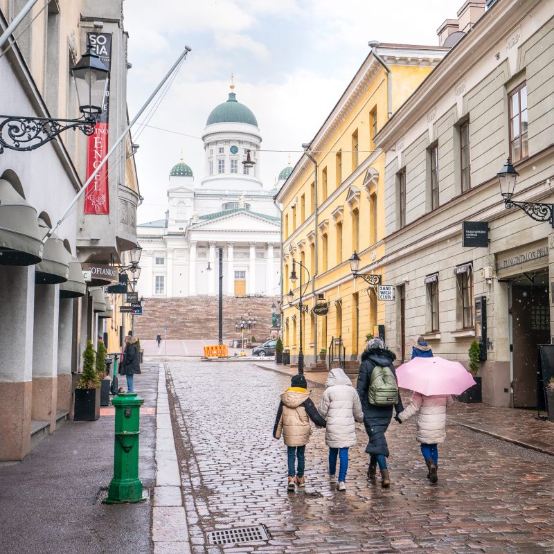 A family walking in the rain towards the Helsinki Cathedral.